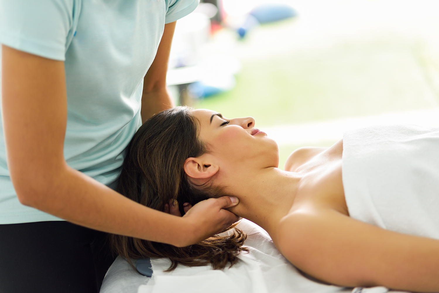 professional female physiotherapist giving shoulder massage to blonde woman